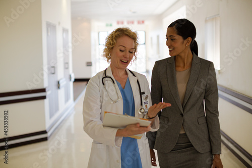 Doctor and businesswoman walking in hospital corridor