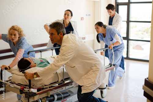 Doctors rushing patient on gurney in hospital corridor