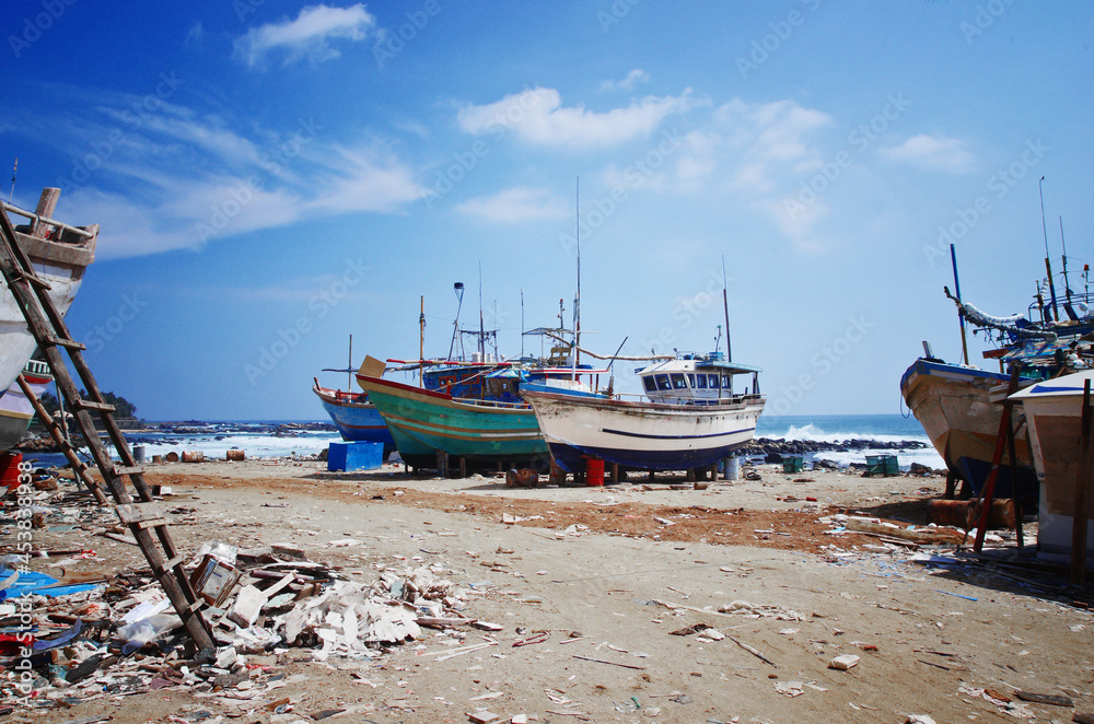 Dondra port, Sri Lanka. Abandoned fishing boats on the shore. Dirty harbor and old ships.