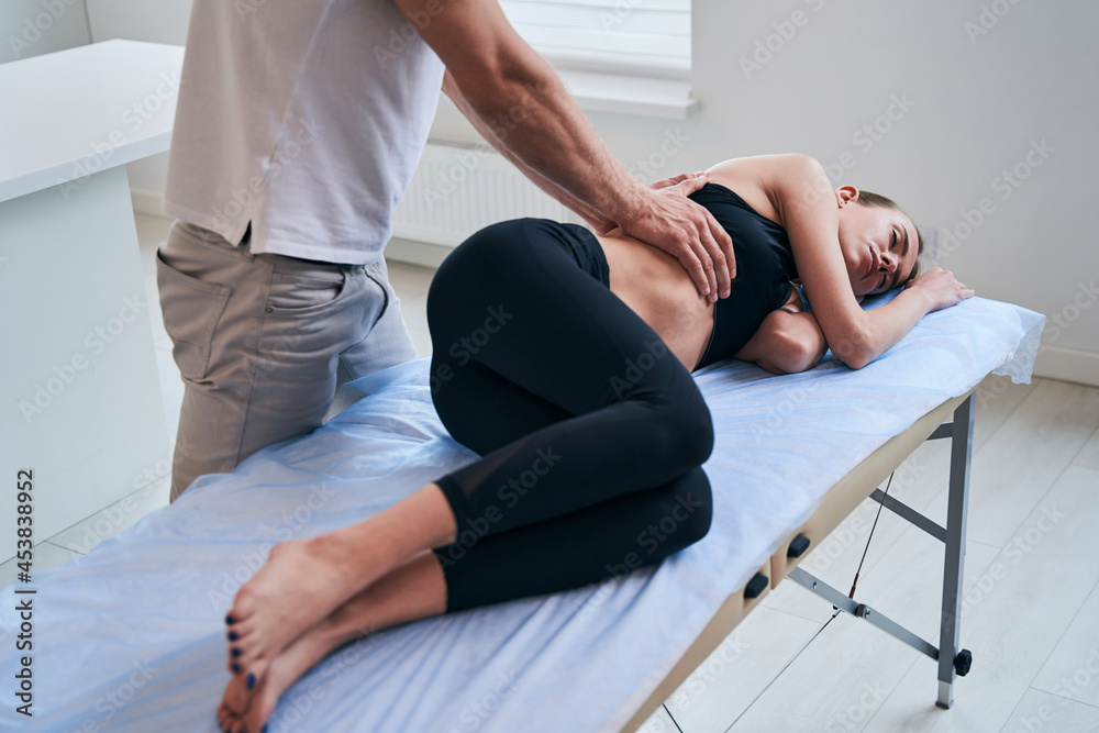 Young attractive Caucasian woman receiving professional rehabilitation procedure in medical office
