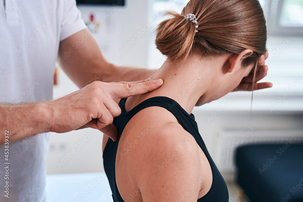 Unrecognized charming female patient sitting in medical office during the manual therapy