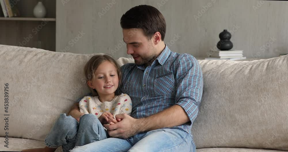 Loving young father embrace cute little girl during warm trustworthy conversation at home, family share news, dad give advice. Communication, trusting relationships between parent and child concept Loving young father embrace cute little girl during warm trustworthy conversation at home, family share news, dad give advice. Communication, trusting relationships between parent and child concept