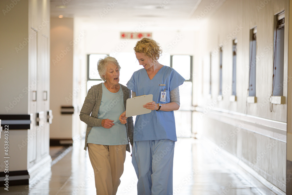 Nurse and aging patient reading chart in hospital corridor Nurse and aging patient reading chart in hospital corridor