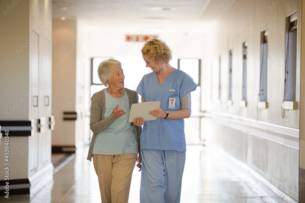 Nurse and aging patient reading chart in hospital corridor Nurse and aging patient reading chart in hospital corridor