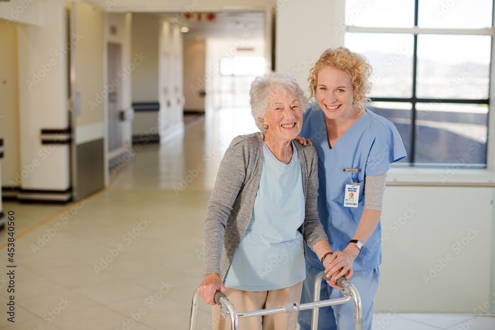 Fototapeta premium Nurse helping senior patient with walker in hospital corridor