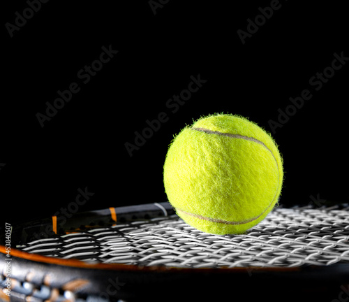 close up of tennis ball on string or net of tennis racquet, racket, on black background for sport for exercise hobby and lifestyle with tennis equipment, net and game competition © kunchainub