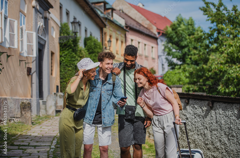 Obraz premium Group of young people outdoors on trip in town, using online map on smartphone.