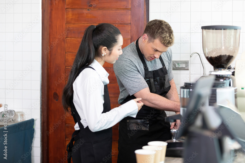 barista teaching trainee how to make a coffee from machine before opening in coffee shop barista teaching trainee how to make a coffee from machine before opening in coffee shop