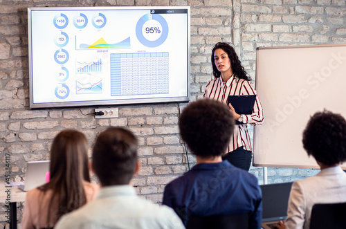 Young business woman holding presentation to diverse group of people.