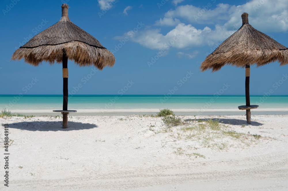 A tropical beach with two straw umbrellas. Vacation concept tropical beach island of Holbox, Mexico