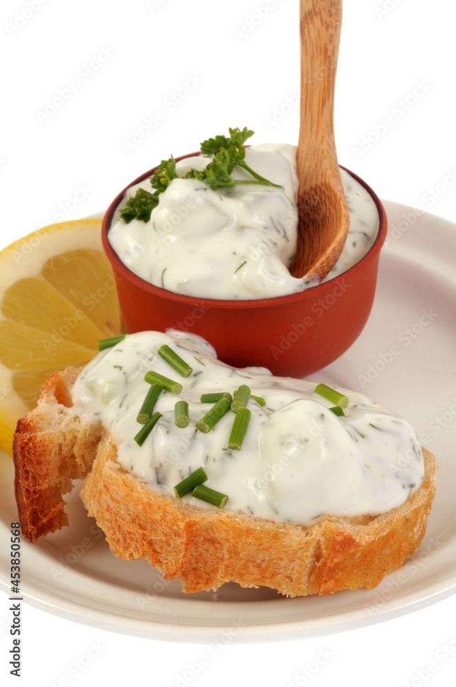 Tartine de tzatziki avec de la ciboulette dans une assiette avec une rondelle de citron en gros plan Tartine de tzatziki avec de la ciboulette dans une assiette avec une rondelle de citron en gros plan