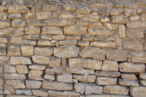 The rough textured surface of the wild stone wall. Background.