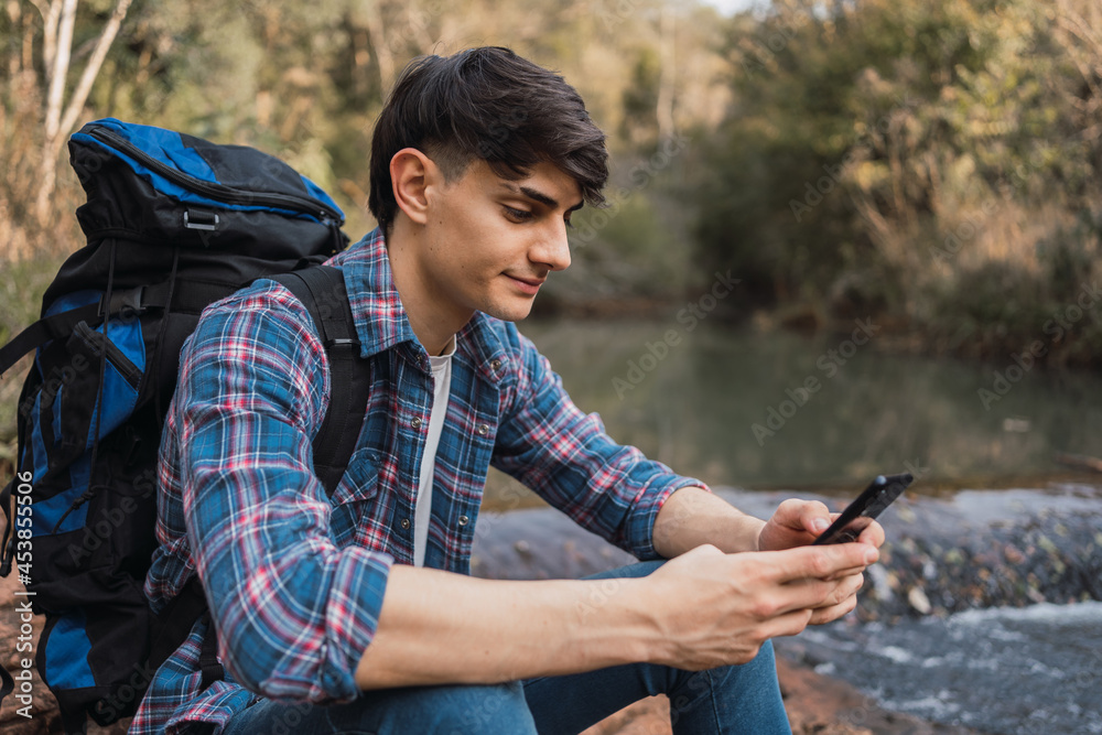 Smiling traveling man using smartphone during hike Smiling traveling man using smartphone during hike