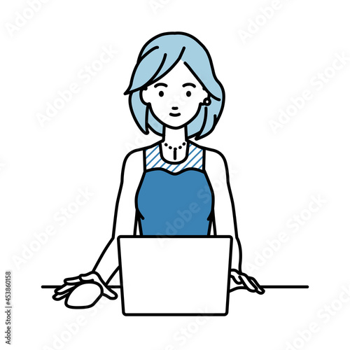 デスクで座ってPCを使っているドレスの女性