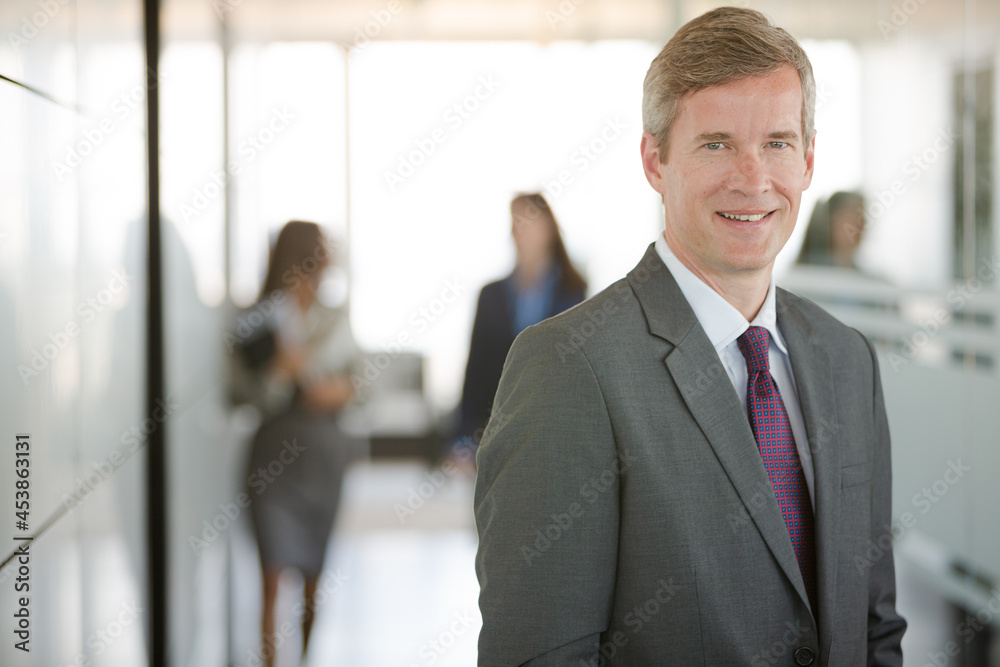 Businessman smiling in office hallway Businessman smiling in office hallway