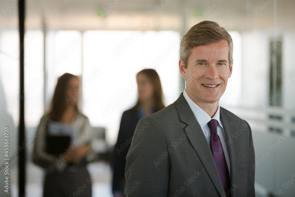 Businessman smiling in office hallway Businessman smiling in office hallway