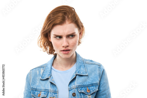 Unsure in bewilderment girl student with red hair shrugs shoulders, makes an interrogative gesture, has an ignorant and confused look, Woman on a white isolated background. What's the difference?