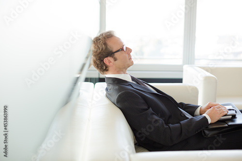 Businessman sitting on sofa in office lobby