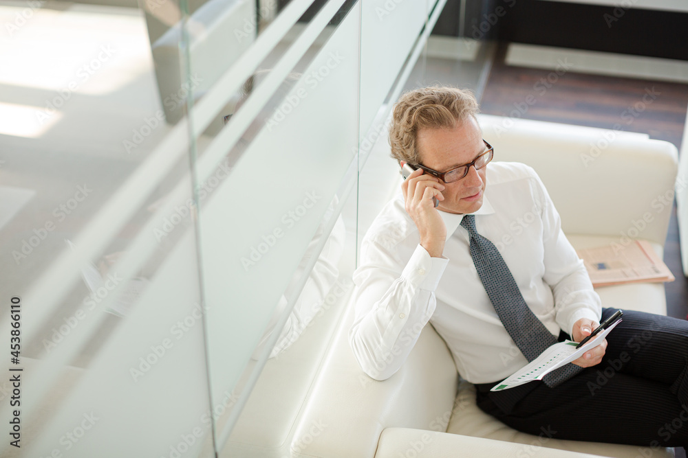 Businessman sitting on sofa in office lobby Businessman sitting on sofa in office lobby