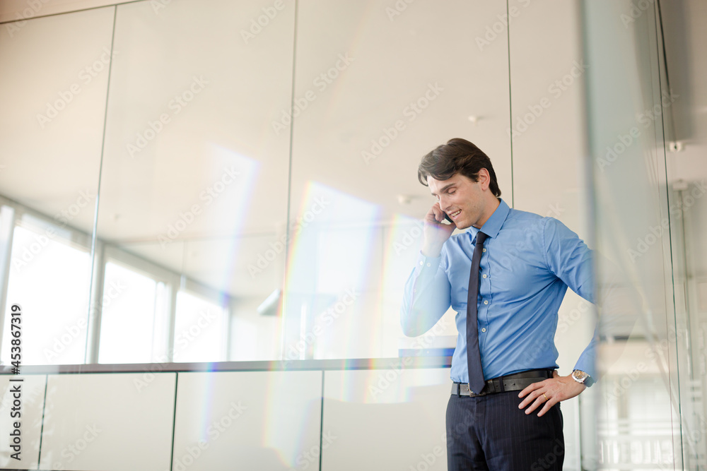 Businessman talking on cell phone in office Businessman talking on cell phone in office