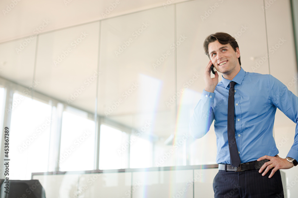 Businessman talking on cell phone in office Businessman talking on cell phone in office