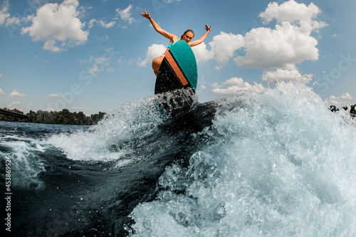 Great view of splashing river wave and active woman with wakesurf skilfully jumping on it
