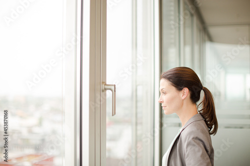 Businesswoman standing at office window Free Download Businesswoman standing at office window - GFXLoad