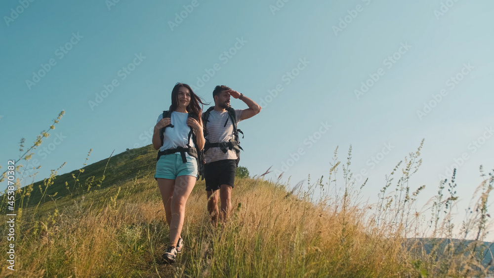 The couple of tourists hiking with backpacks