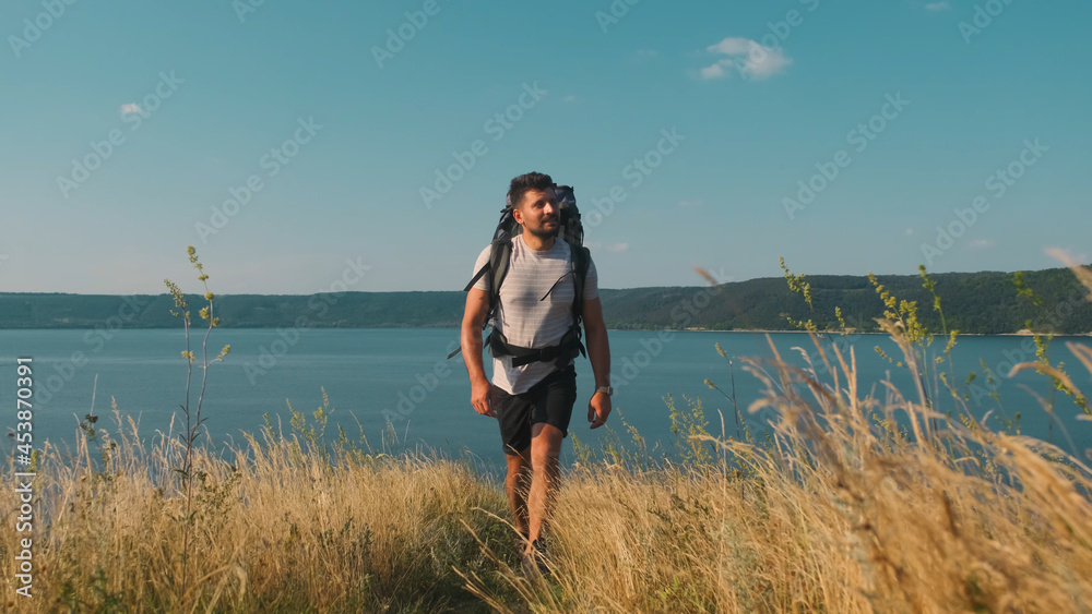 The handsome man walking with backpack along the coast The handsome man walking with backpack along the coast