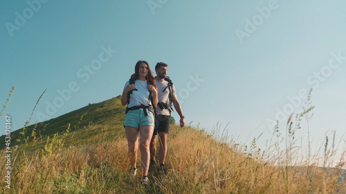 The couple of tourists hiking with backpacks