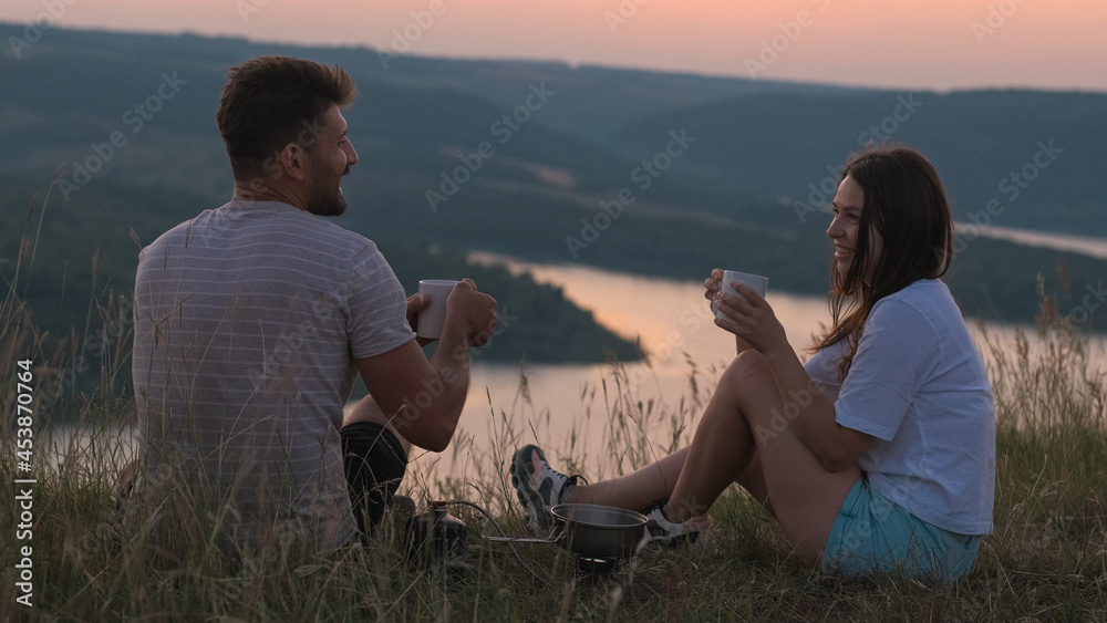 The happy couple sitting on mountain top and drinking tea