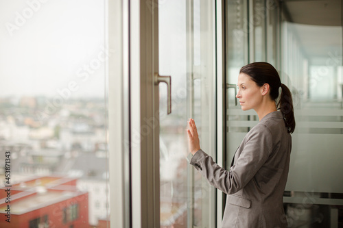 Free Download Businesswoman standing at office window - GFXLoad