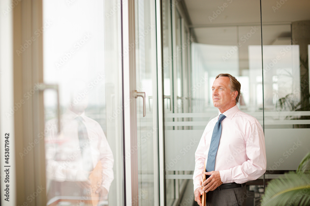 Businessman standing at office window Businessman standing at office window