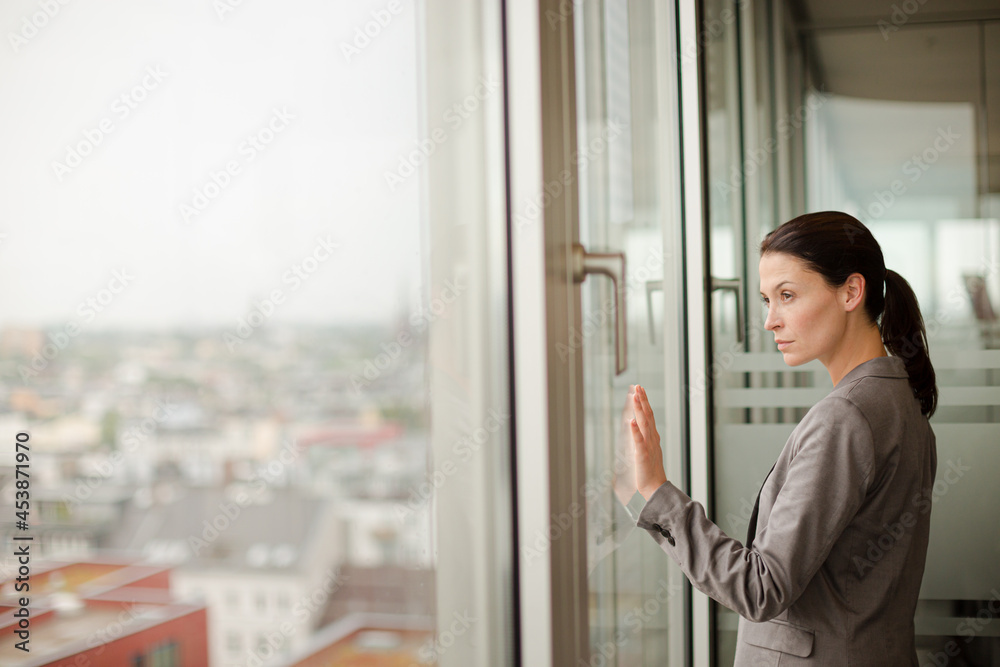 Businesswoman standing at office window Businesswoman standing at office window