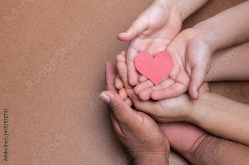 Fototapeta Naklejka Na Ścianę i Meble -  hands holding red heart image, chocolate background