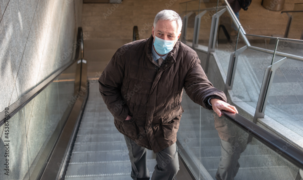 Masked man lifting an escalator, coronavirus concept