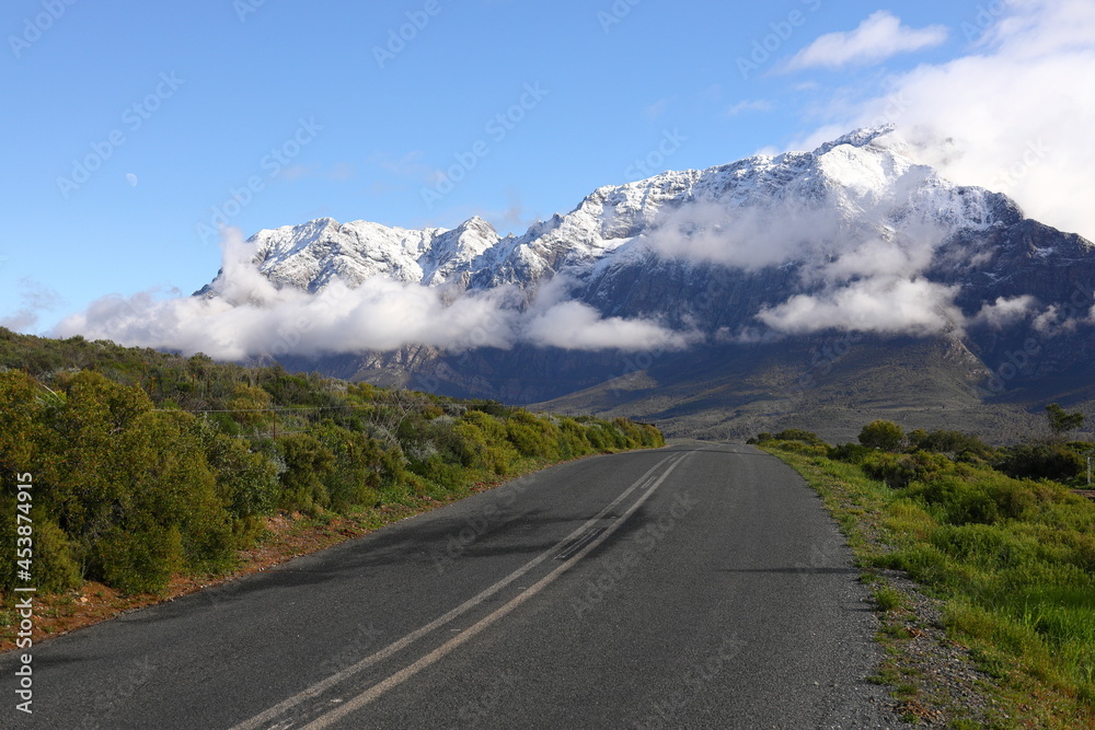 Naklejka premium A view over green hills towards snow covered peaks