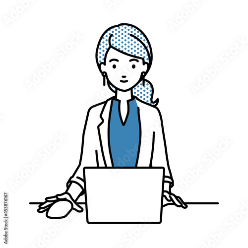 デスクで座ってPCを使っているジャケットの女性