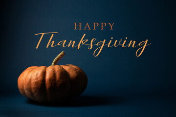 Dark moody Thanksgiving background with orange pumpkin and holiday copy space.