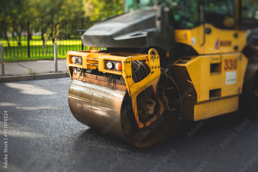 Obraz premium Process of asphalting, blacktopping and paving, asphalt paver machine and steam roller compactor during construction and repairing works, workers on the construction site, rental vehicle working