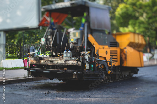 Process of asphalting, blacktopping and paving, asphalt paver machine and steam roller compactor during construction and repairing works, workers on the construction site, rental vehicle working