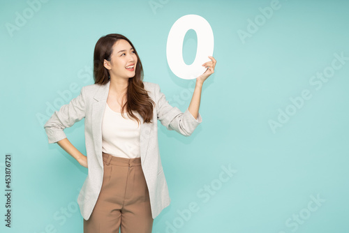 Young beautiful Asian businesswoman showing number 0 or zero isolated on green background