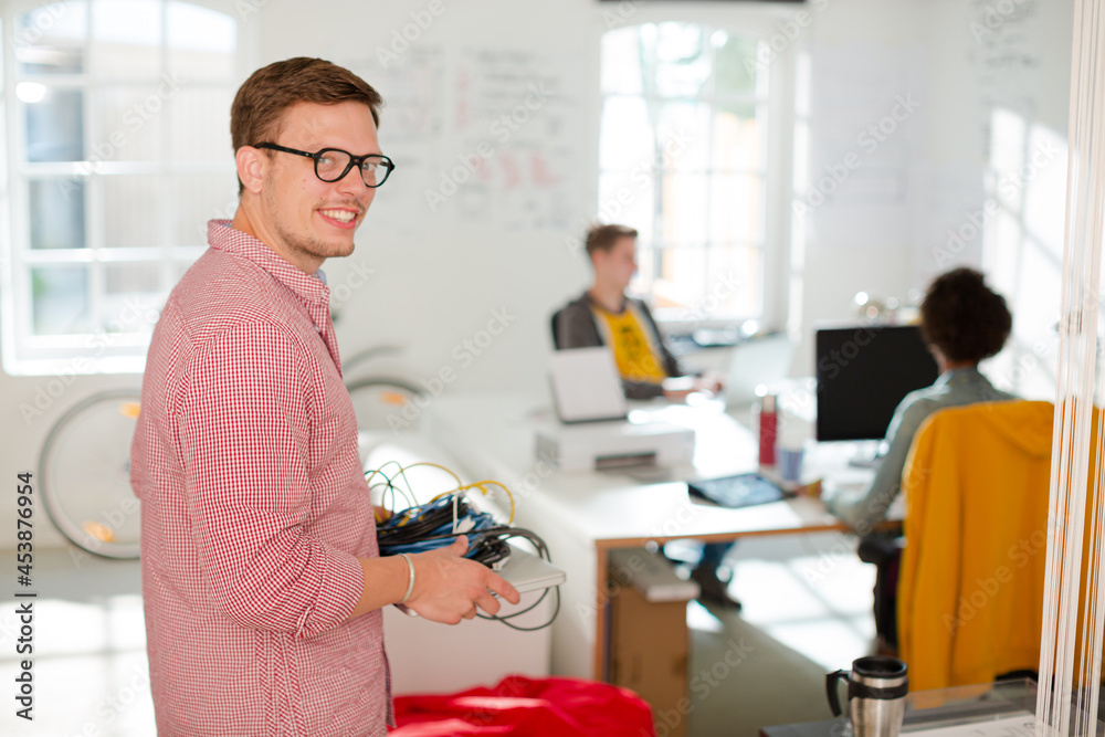 Businessman carrying cords and laptop in office