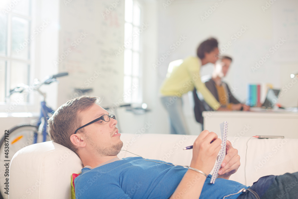 Obraz premium Businessman taking notes on sofa in office
