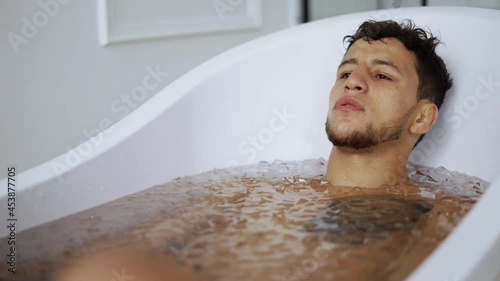 Man sits with closed eyes in the bath with ice cubes for recovery photo