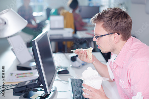 Businessman eating Chinese food at desk