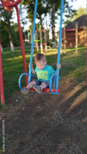 child playing on playground. Little boy swinging on a swing. Children's swing in the park. Playground for children.