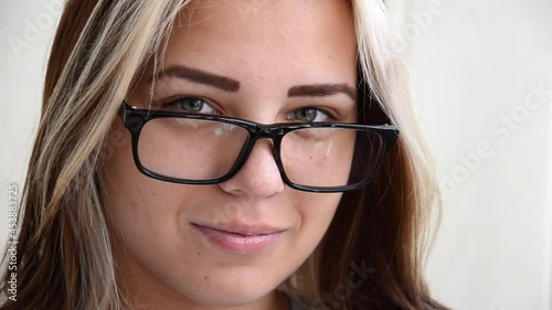 Brunette young woman with glasses. Concept of choosing profession. Beautiful caucasian young girl with green eyes looks at camera and smiles. Student, entrant or young employee. 