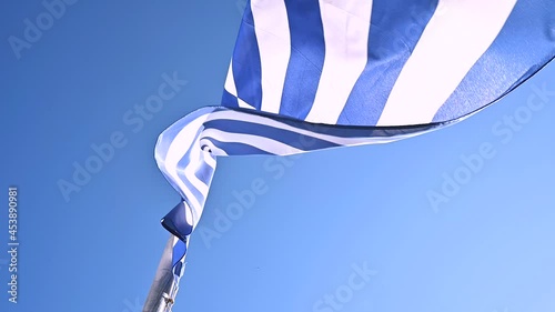 Greek flag waving in slow motion over Greek sun in the background