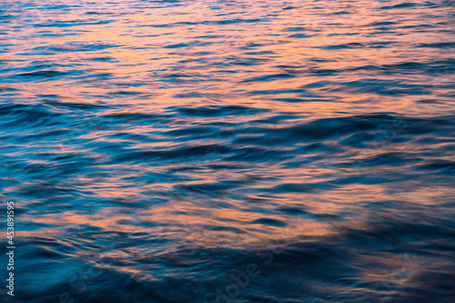 Natural natural background. The color of the ocean with waves in the rays of sunset.